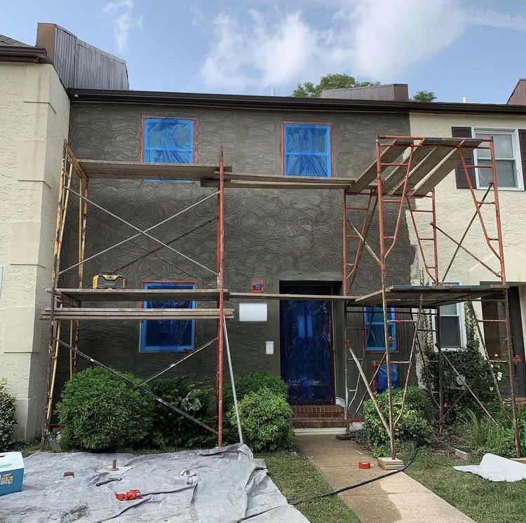 Building facade under construction with scaffolding, windows covered in blue plastic.