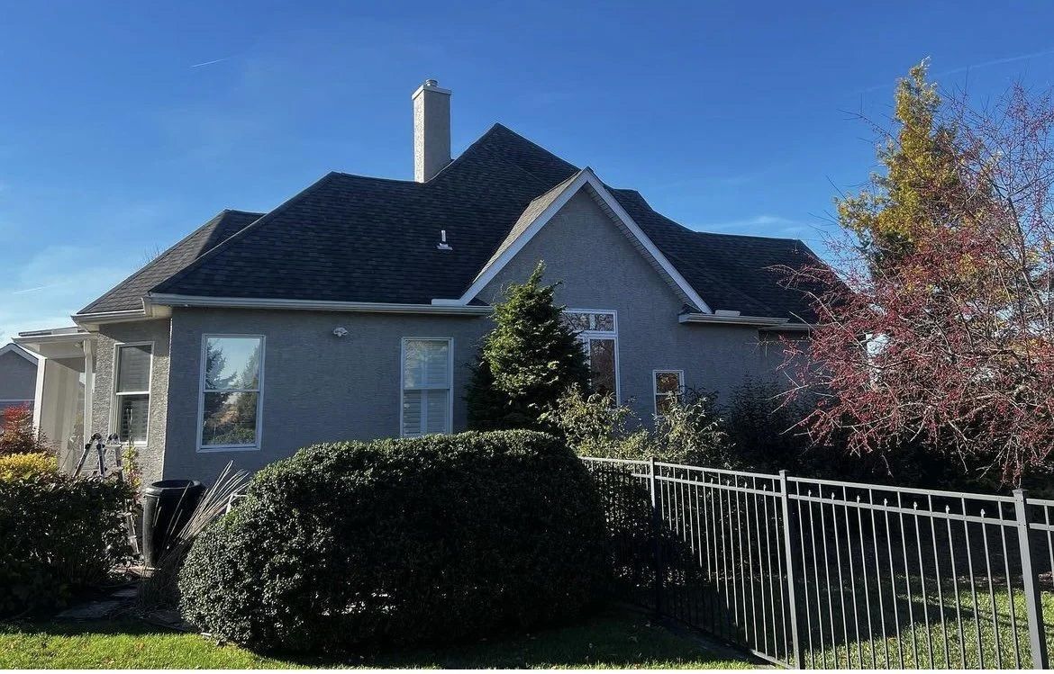 A blue stucco house with a dark roof and a small decorative fence.