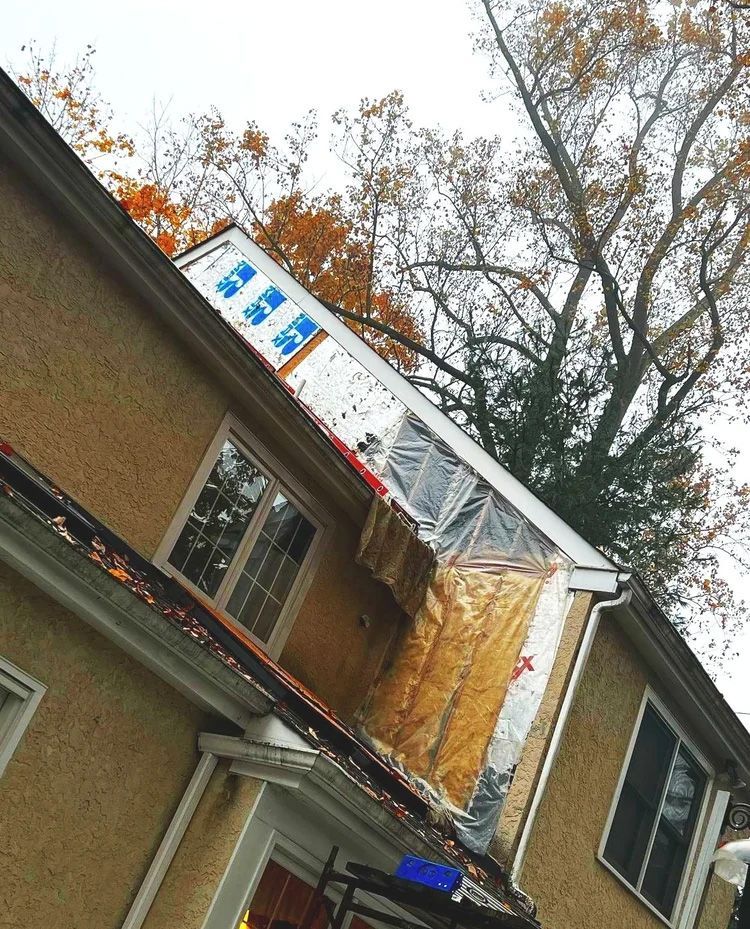 House with roof partially under construction; exposed wood, insulation, and new materials visible.