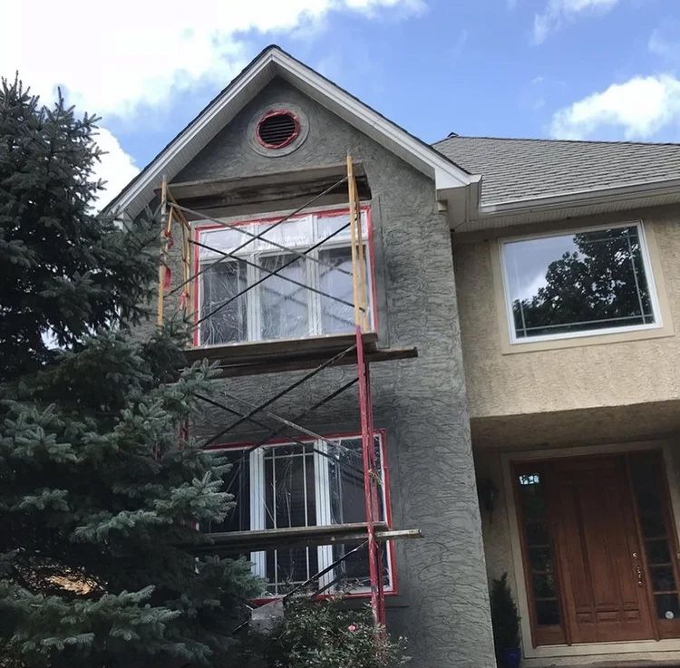 Scaffolding next to a two-story house with window work in progress.