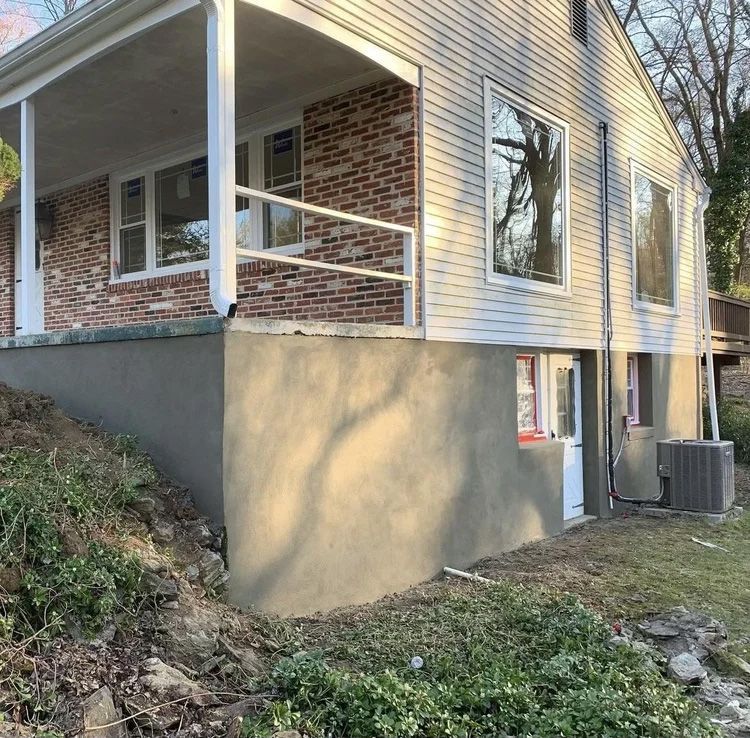 House exterior with porch, brick facade, white siding, and gray foundation.
