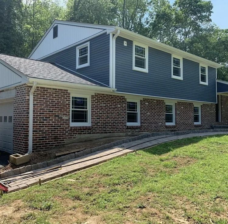 Two-story house with brick base, blue siding, white trim, and a ramp leading to the front door.