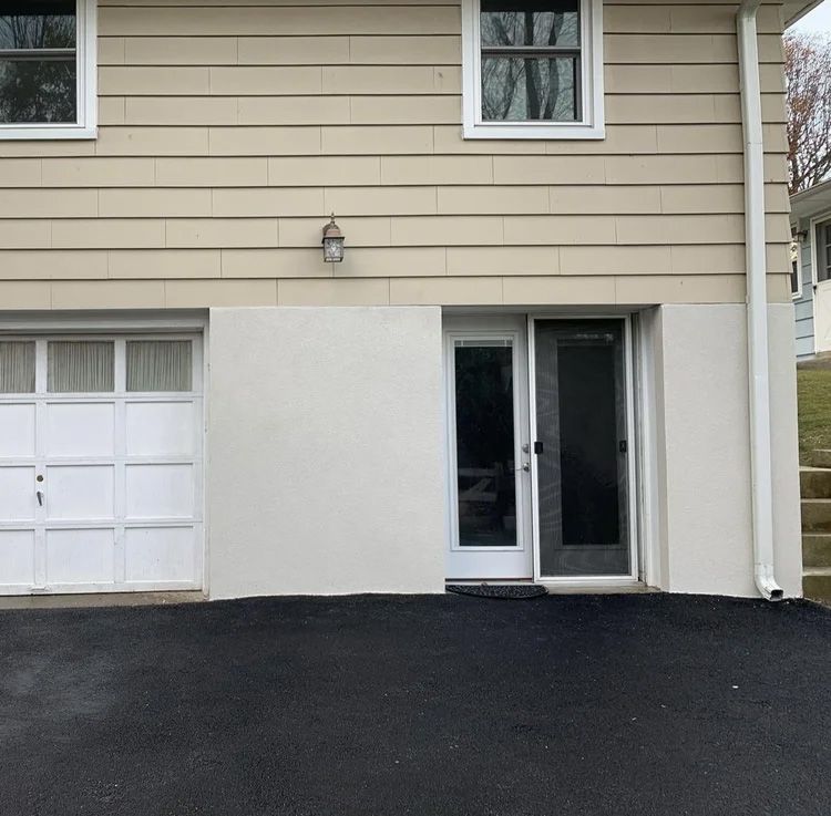 Beige house exterior with garage door, sliding glass door, and asphalt driveway.