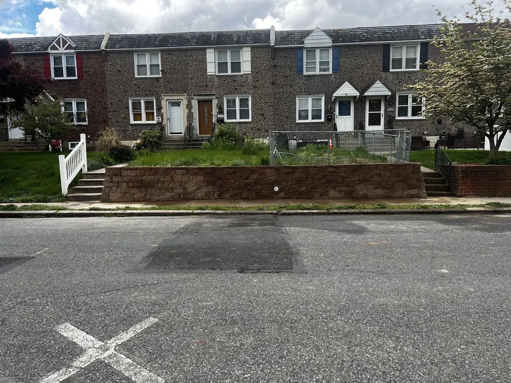 Row houses with brick facades, some with white trim, a small lawn, and a street in front.