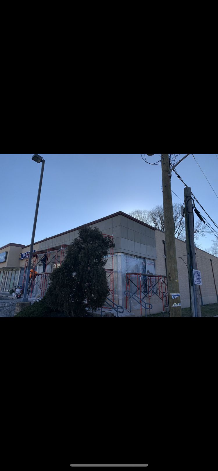 Building with graffiti on the facade, under a clear blue sky, next to power lines and a street lamp.