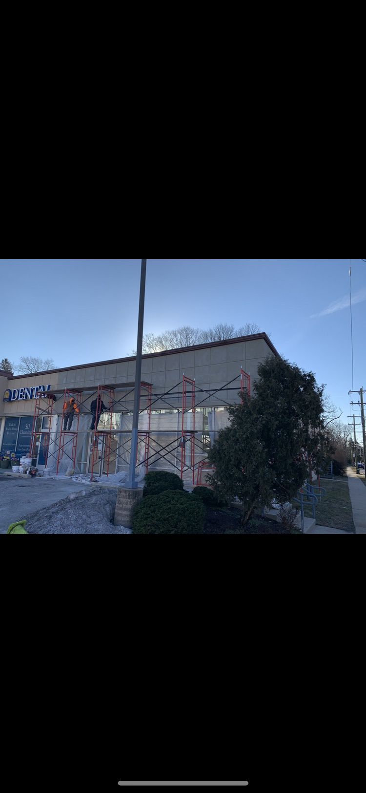Exterior of a building with graffiti. A tree and a utility pole are visible in front. Clear sky.