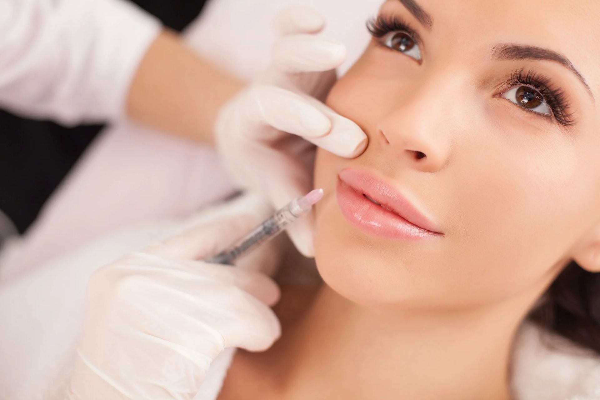 Cosmetic injection being applied to a woman’s face by gloved hands in a clinical setting
