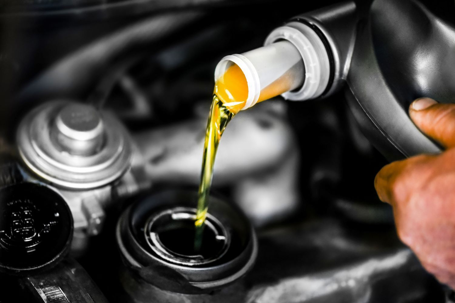 A person is pouring oil into a car engine.