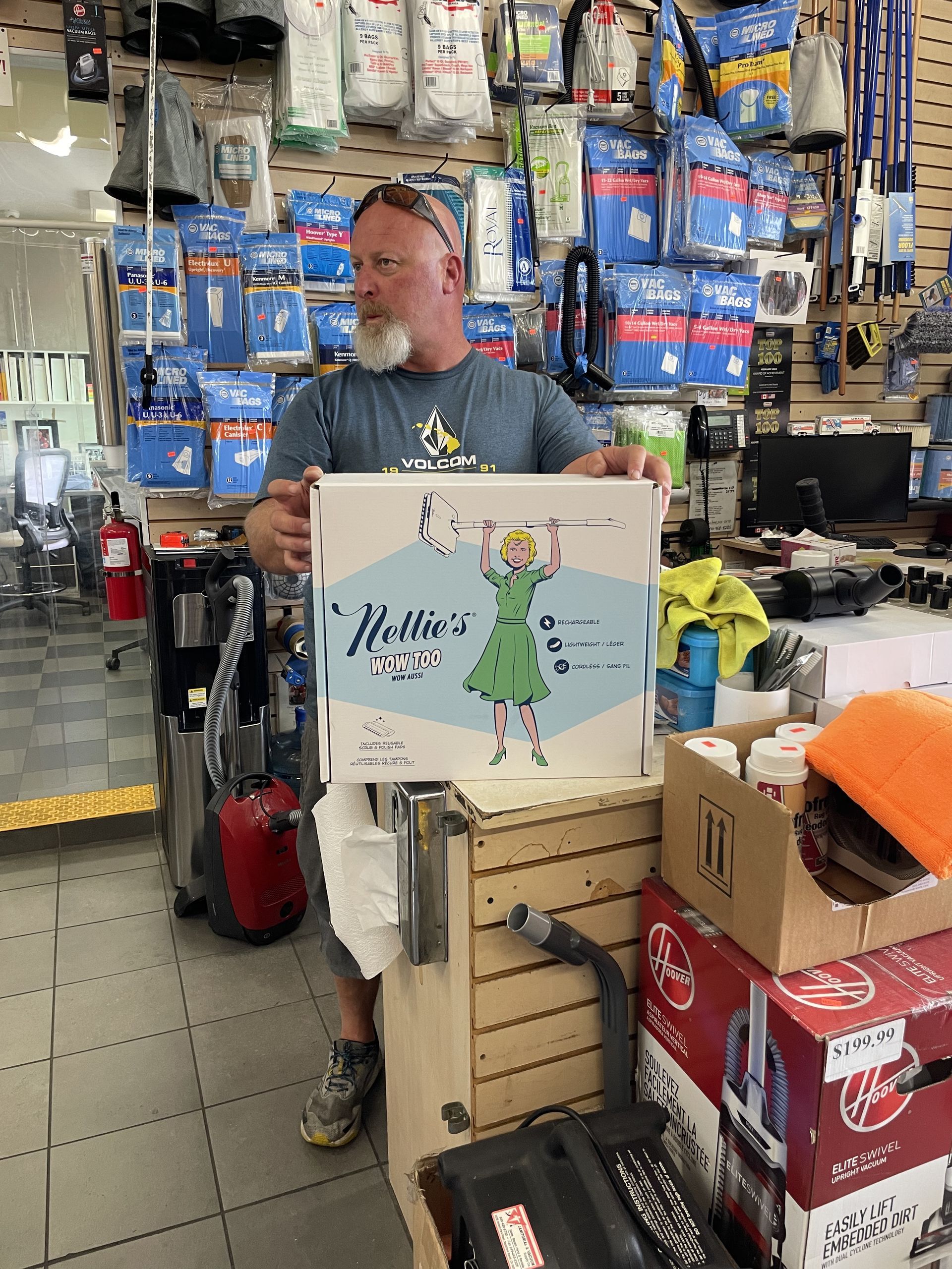 Man in store holding box with cartoon girl illustration. Shelves filled with products.
