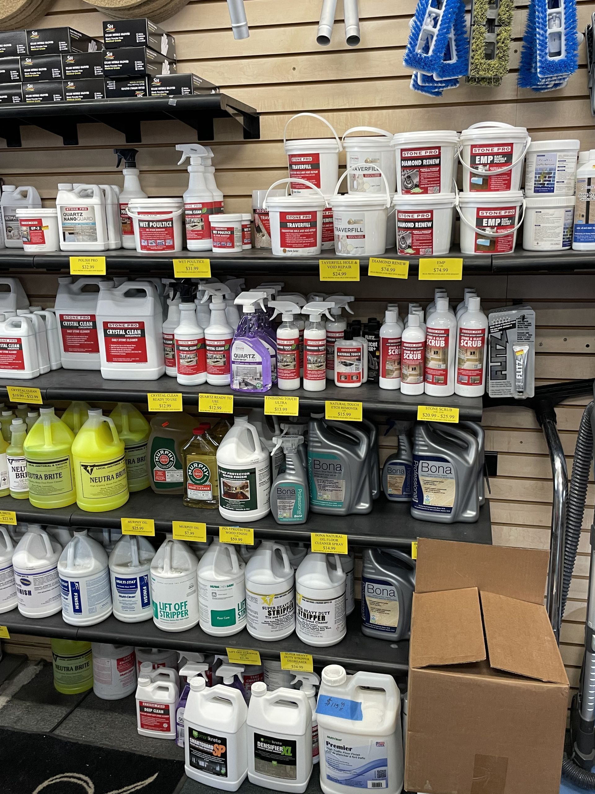 Shelves stocked with various cleaning supplies in containers of different sizes and colors, inside a store.
