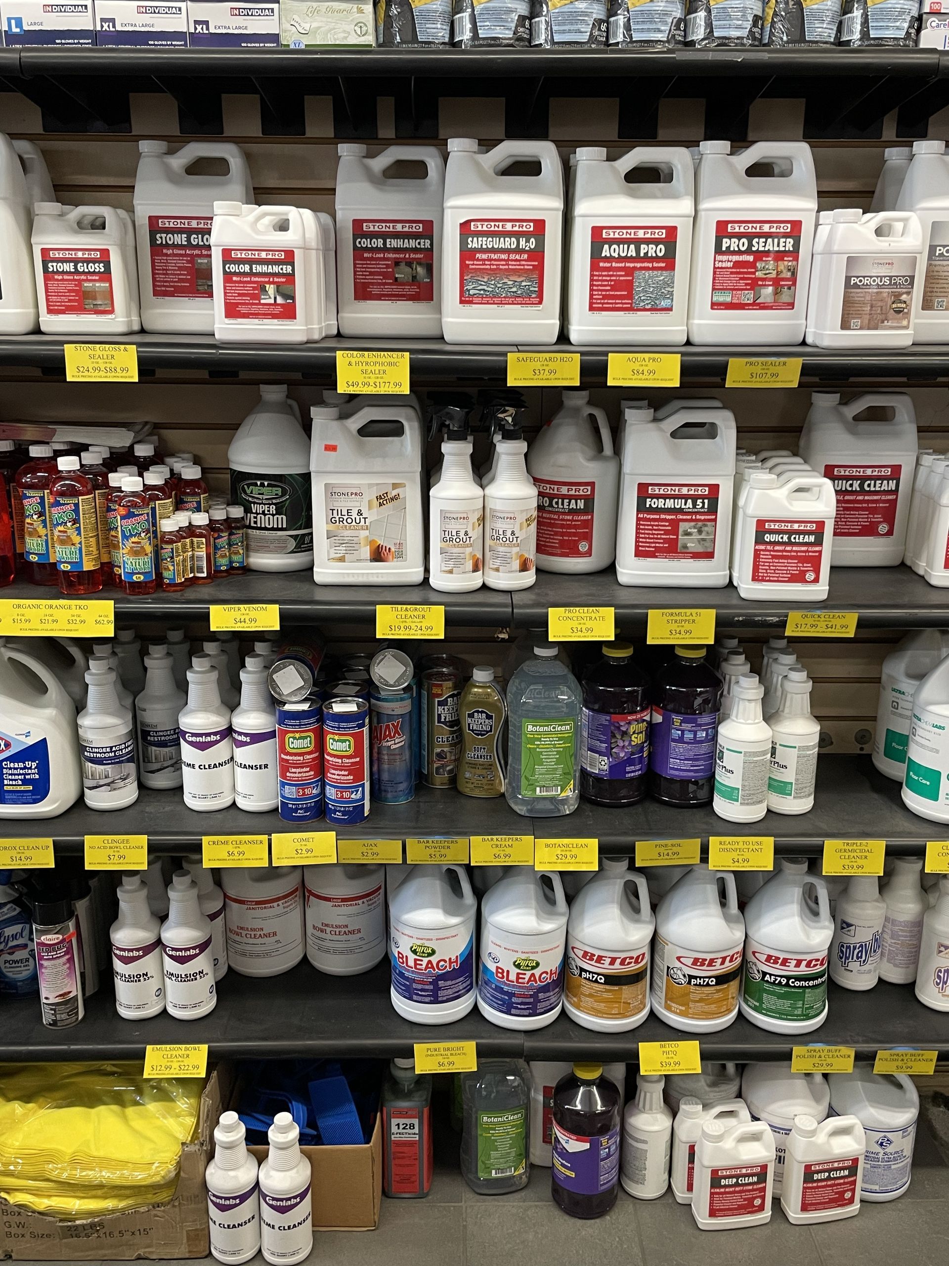 Shelves stocked with various cleaning products in white containers with red labels.