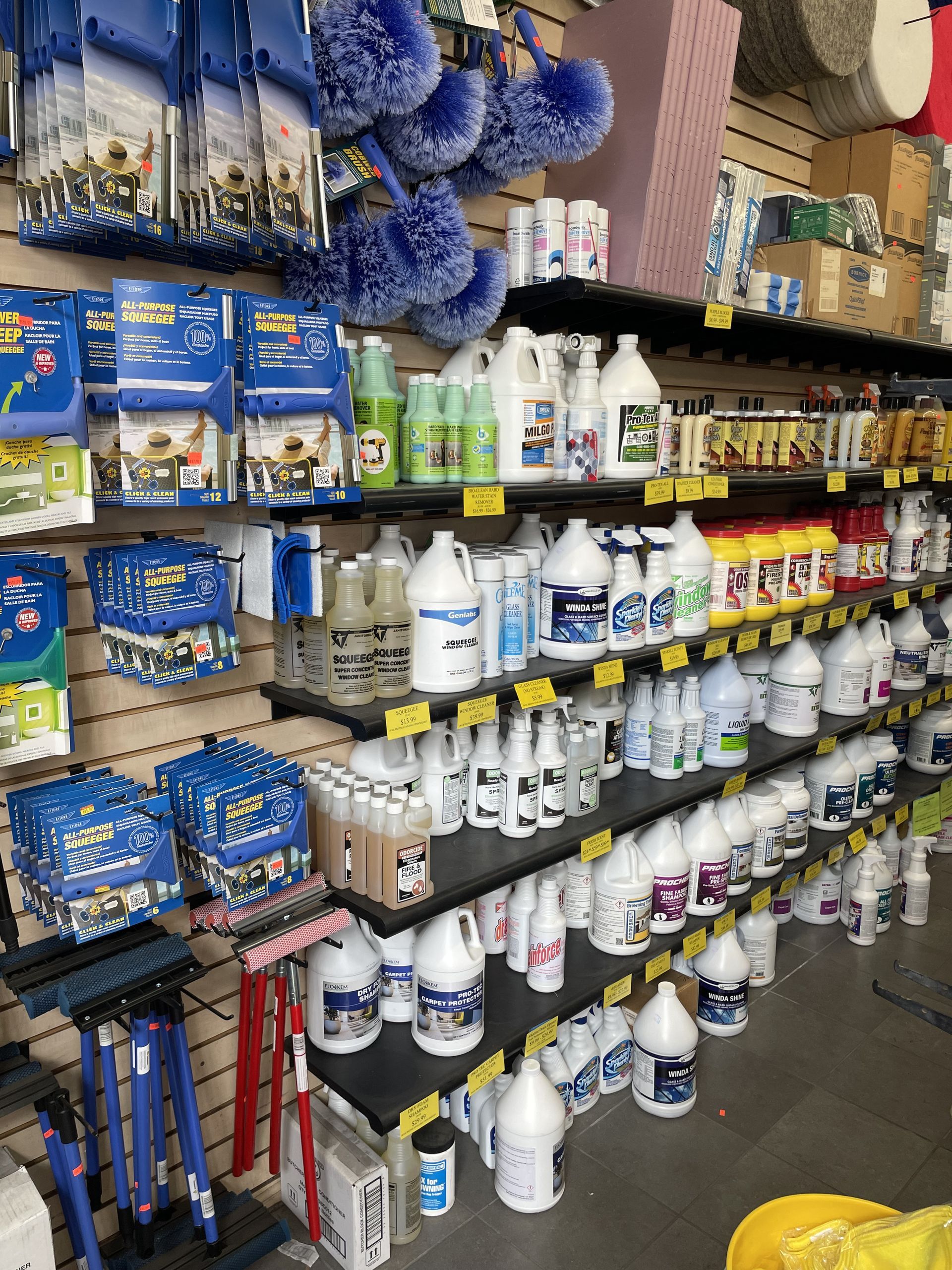 Cleaning supplies on shelves in a store. Various bottles, brushes, and accessories are displayed in rows.