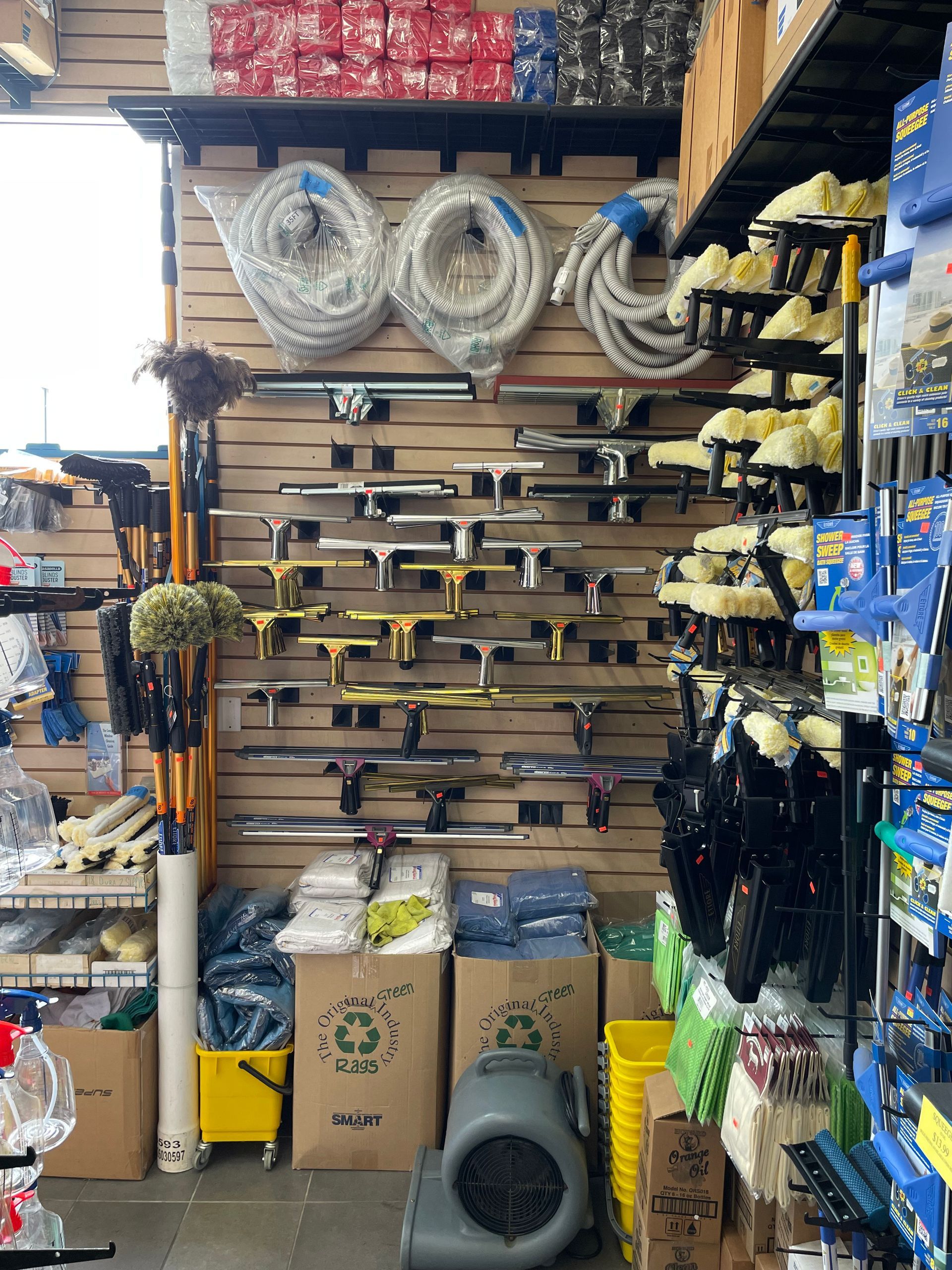 A store display with cleaning supplies: squeegees, hoses, buckets, soaps, and gloves.