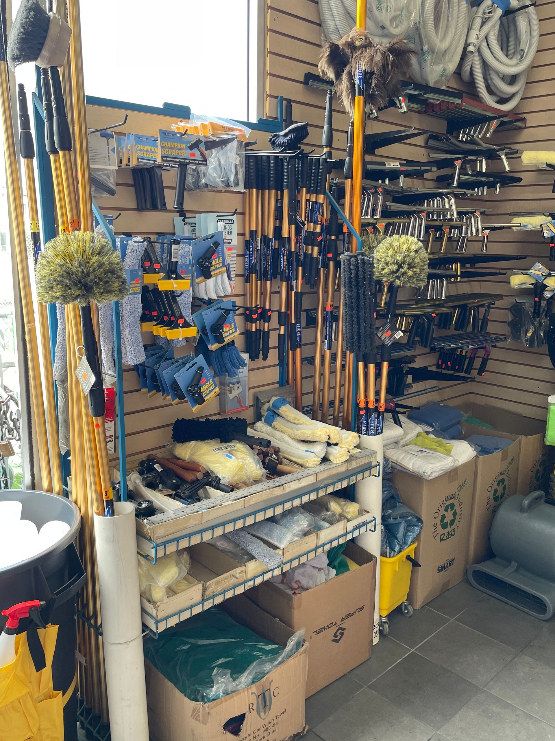 Hardware store display of cleaning supplies: mops, brooms, gloves, sponges, and other tools.