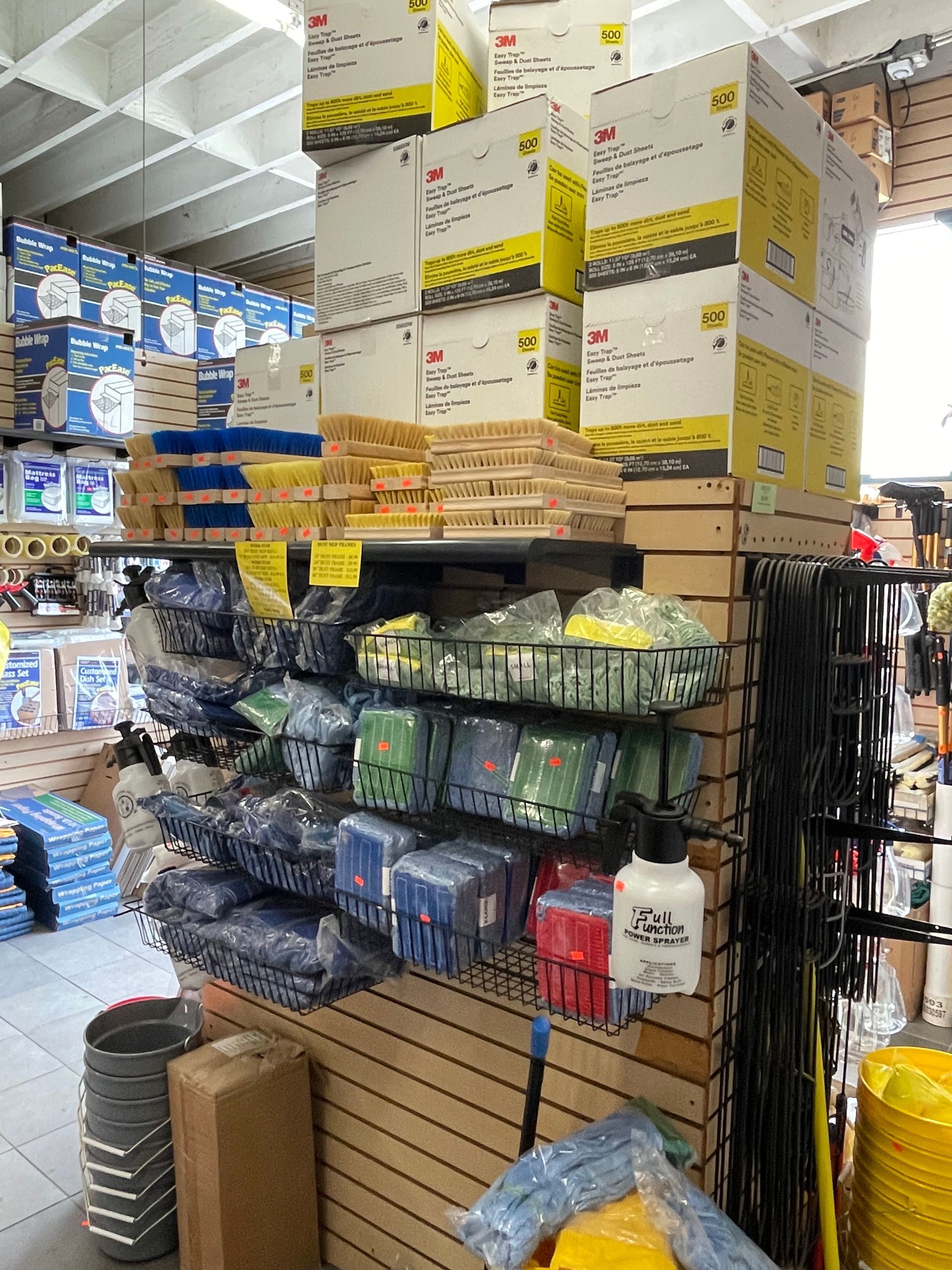 Shelves displaying paint supplies in a store, featuring boxes, brushes, and cleaning tools.