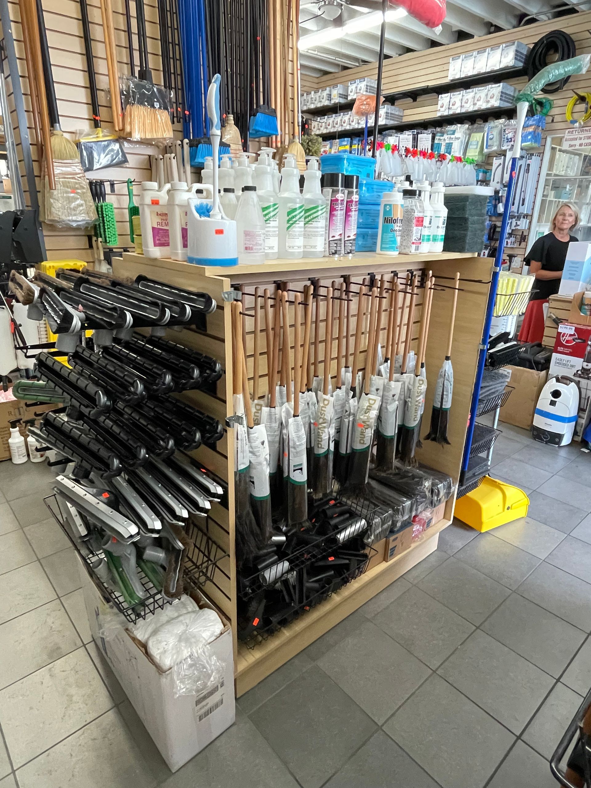 Cleaning supplies on display in a store, including mops, brooms, and cleaning solutions.