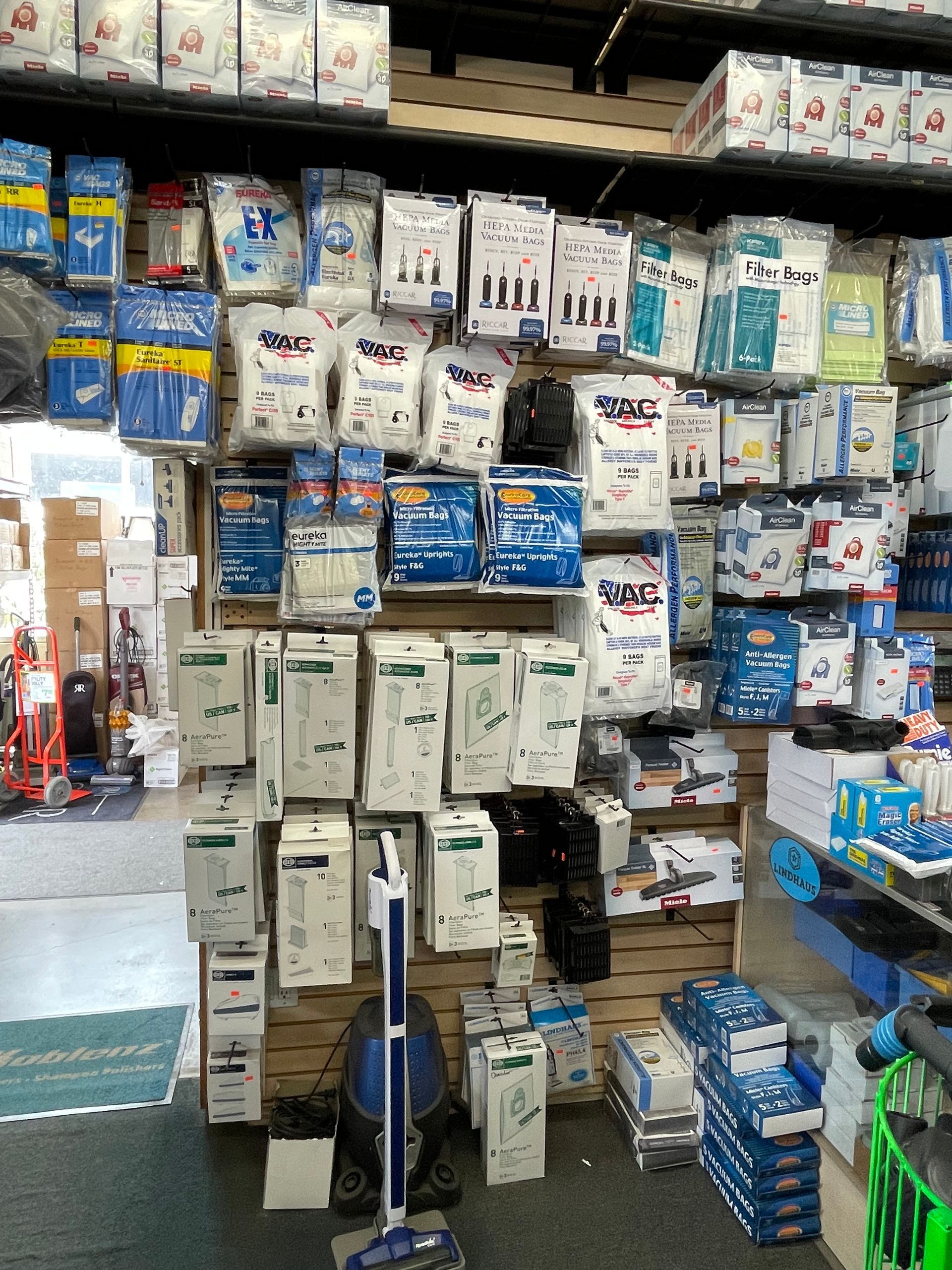 Shelves stocked with medical supplies in a store, including bandages, gloves, and vacuum cleaner.