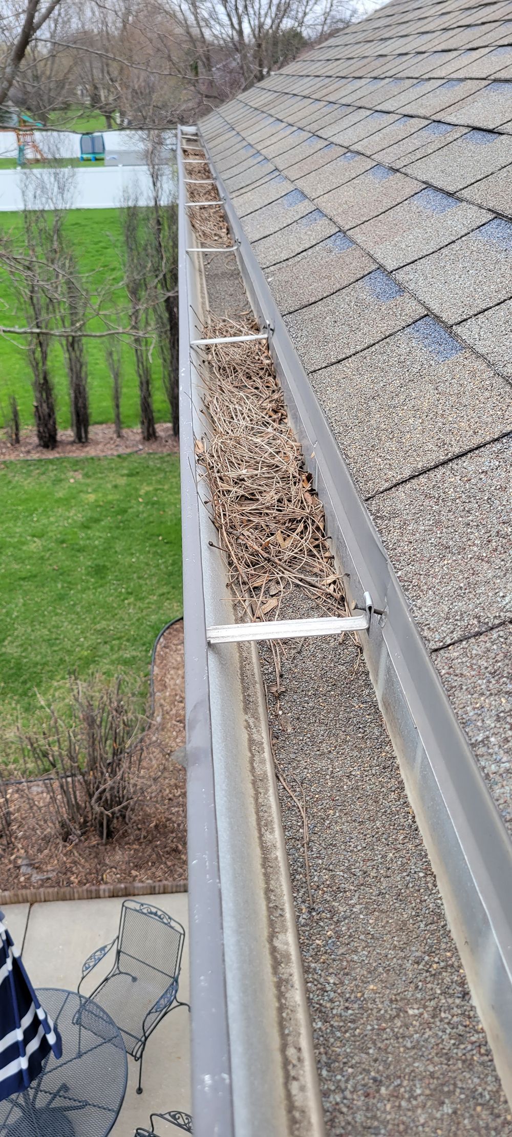 A close up of a gutter on a roof with leaves on it