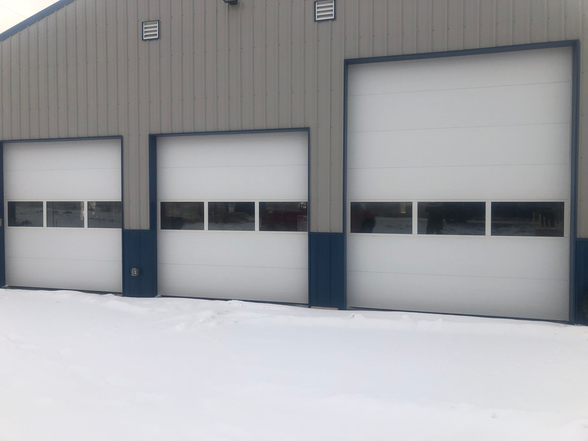 Three garage doors are lined up in front of a building