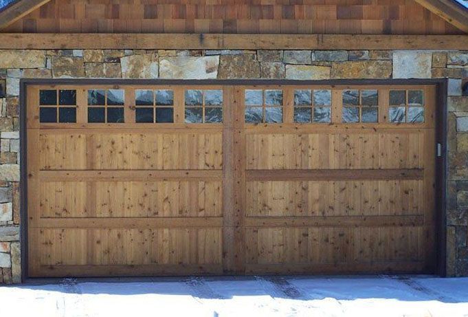 A wooden garage door with a stone wall behind it