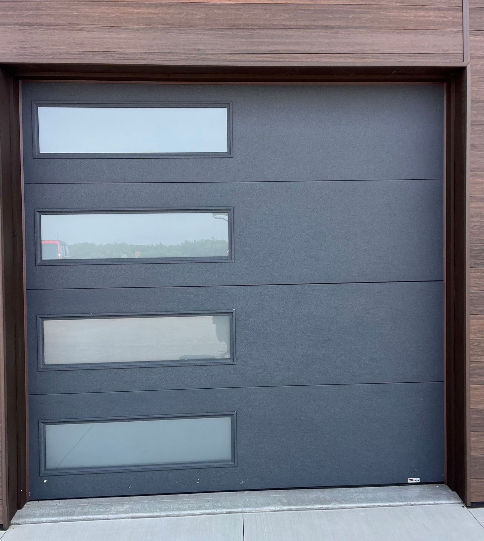A black garage door with three windows on it