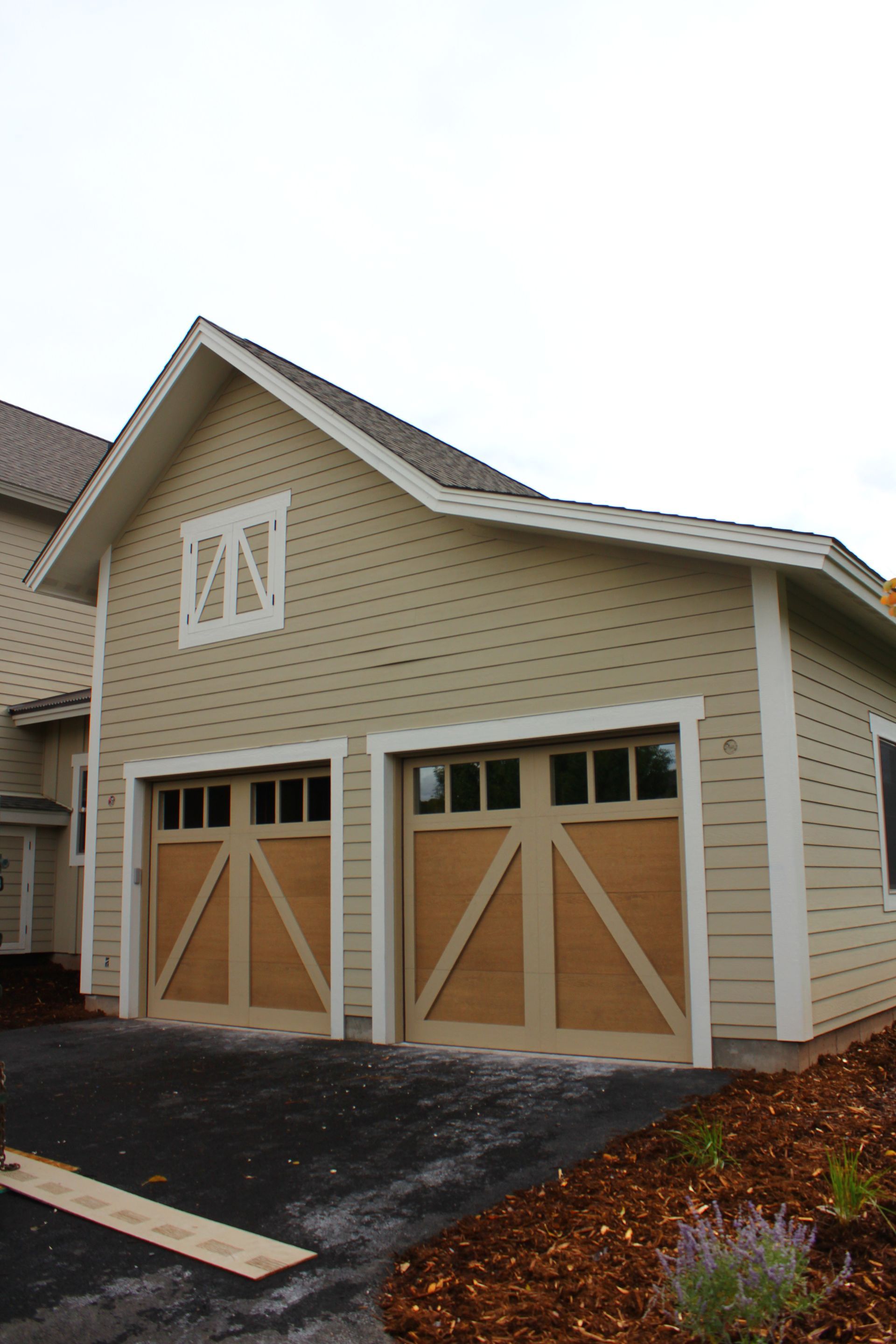 Tan garage with brown doors, white trim, and a small window above.