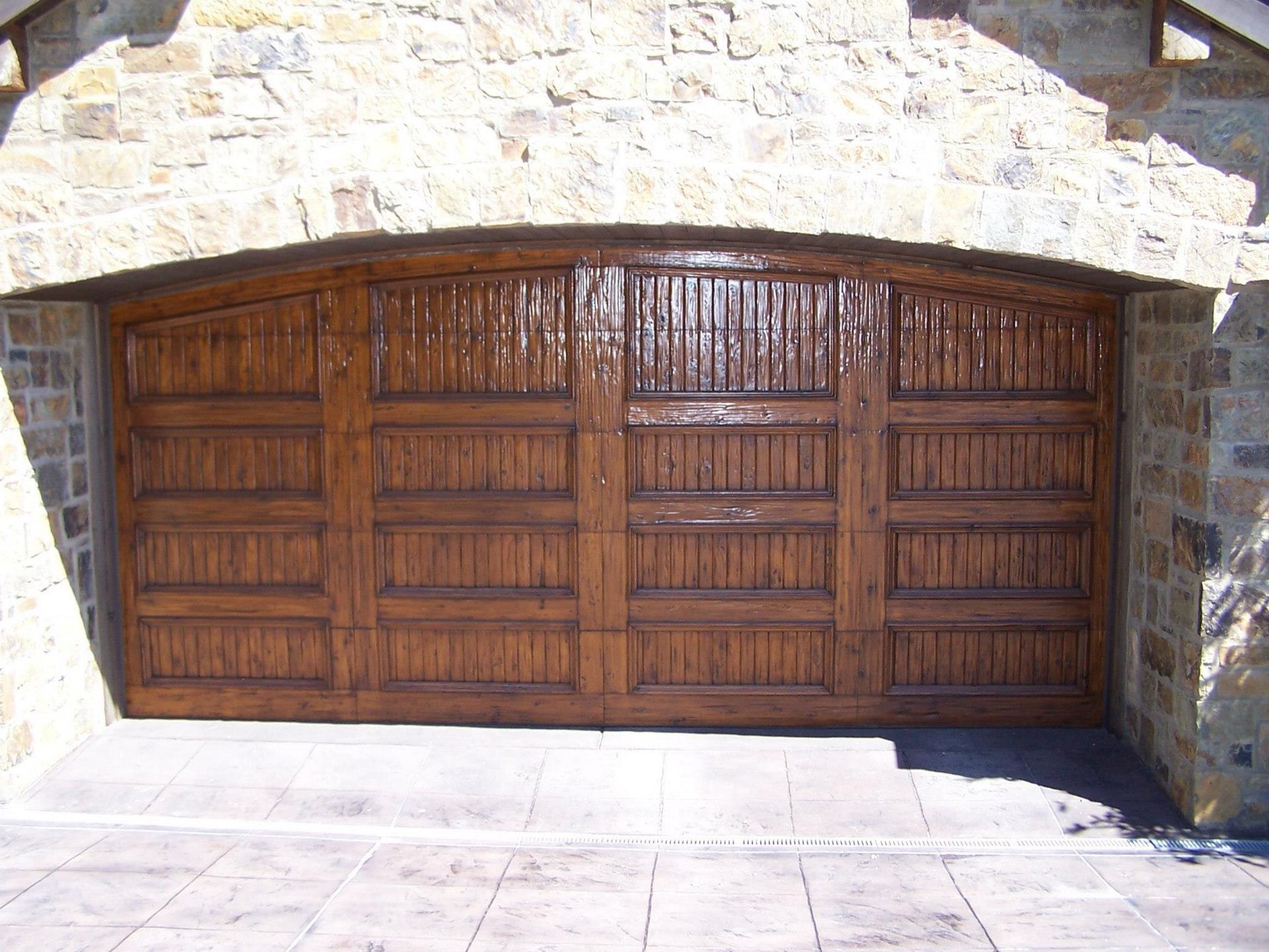 A large wooden garage door with a stone wall behind it