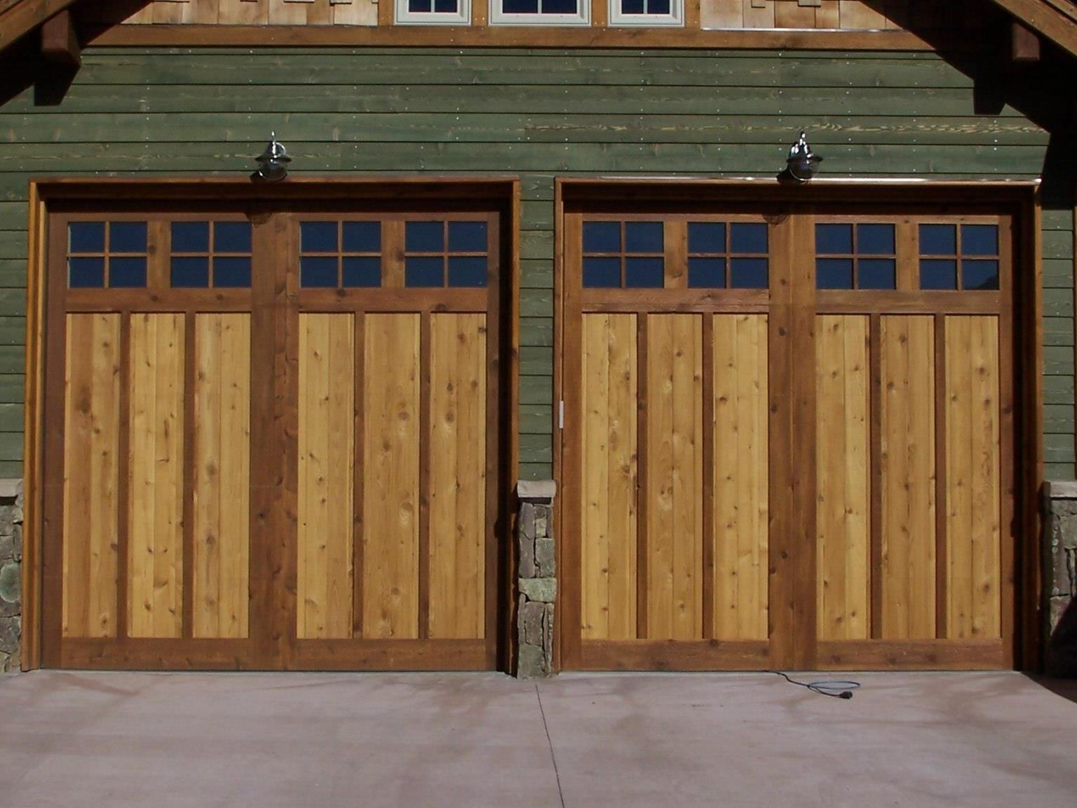 A pair of wooden garage doors on the side of a house