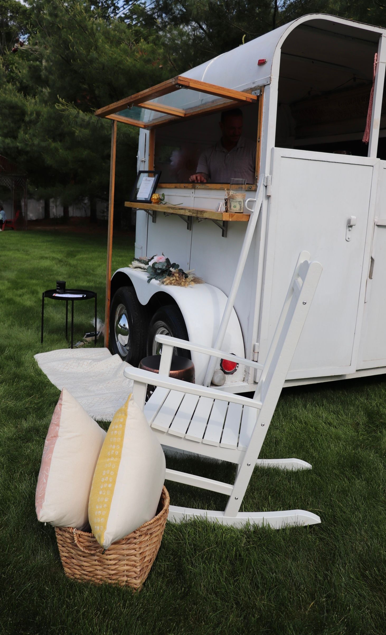 A white rocking chair is sitting in front of a trailer.