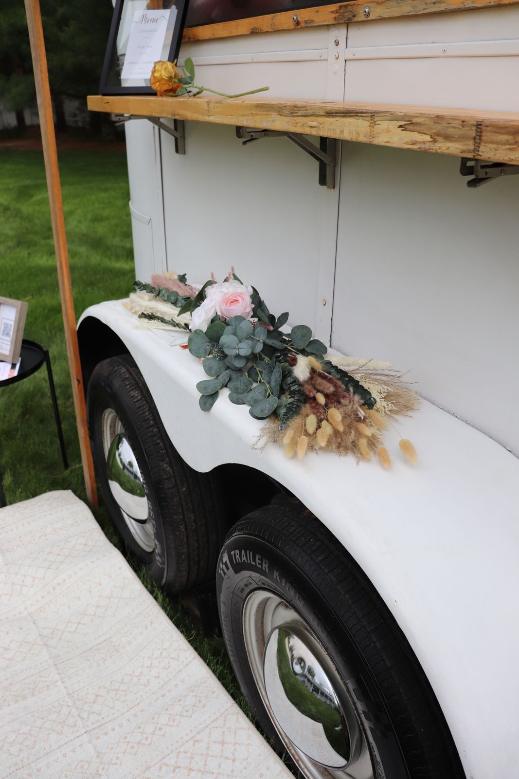 A white trailer with flowers on the side of it.