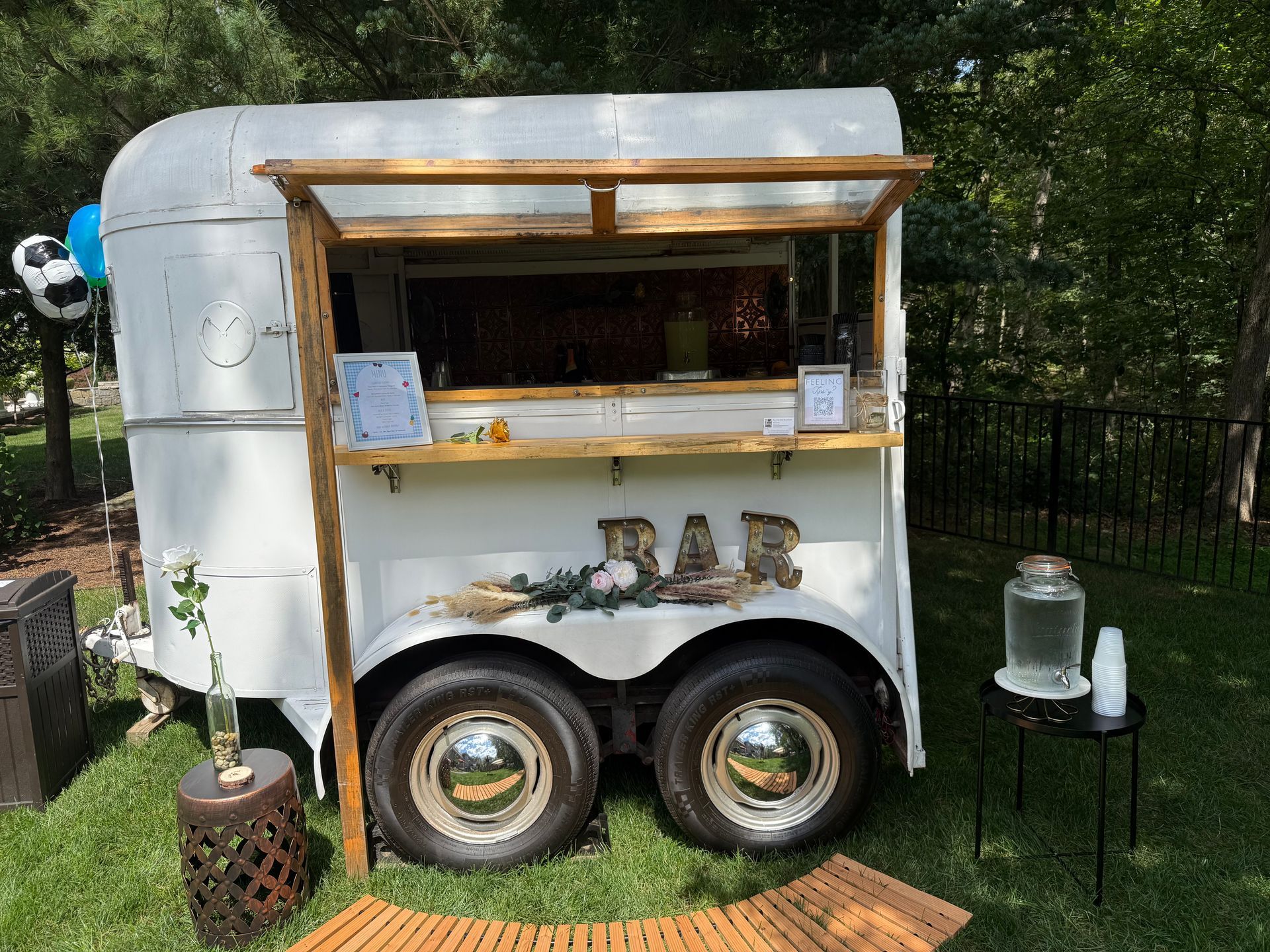 A white trailer with a bar on it is parked in the grass.