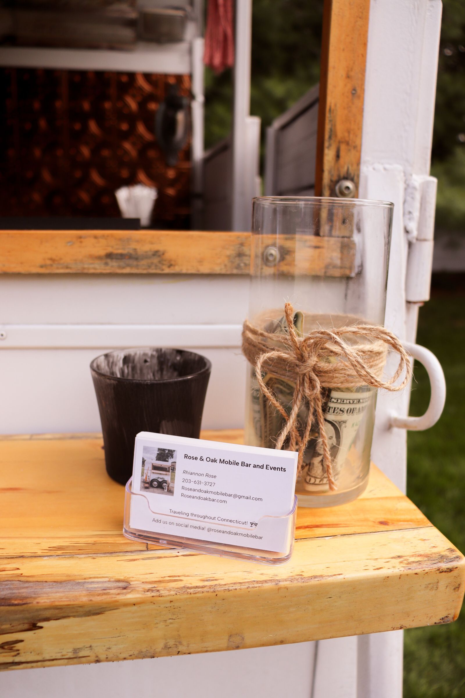 A wooden table with a cup and a card on it.