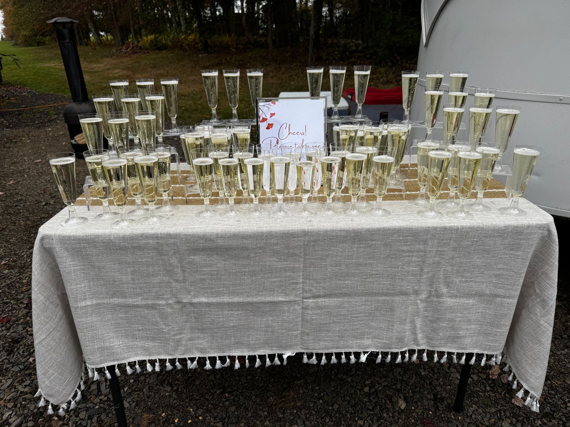 Table set with many champagne glasses; “Bad Decisions” sign.