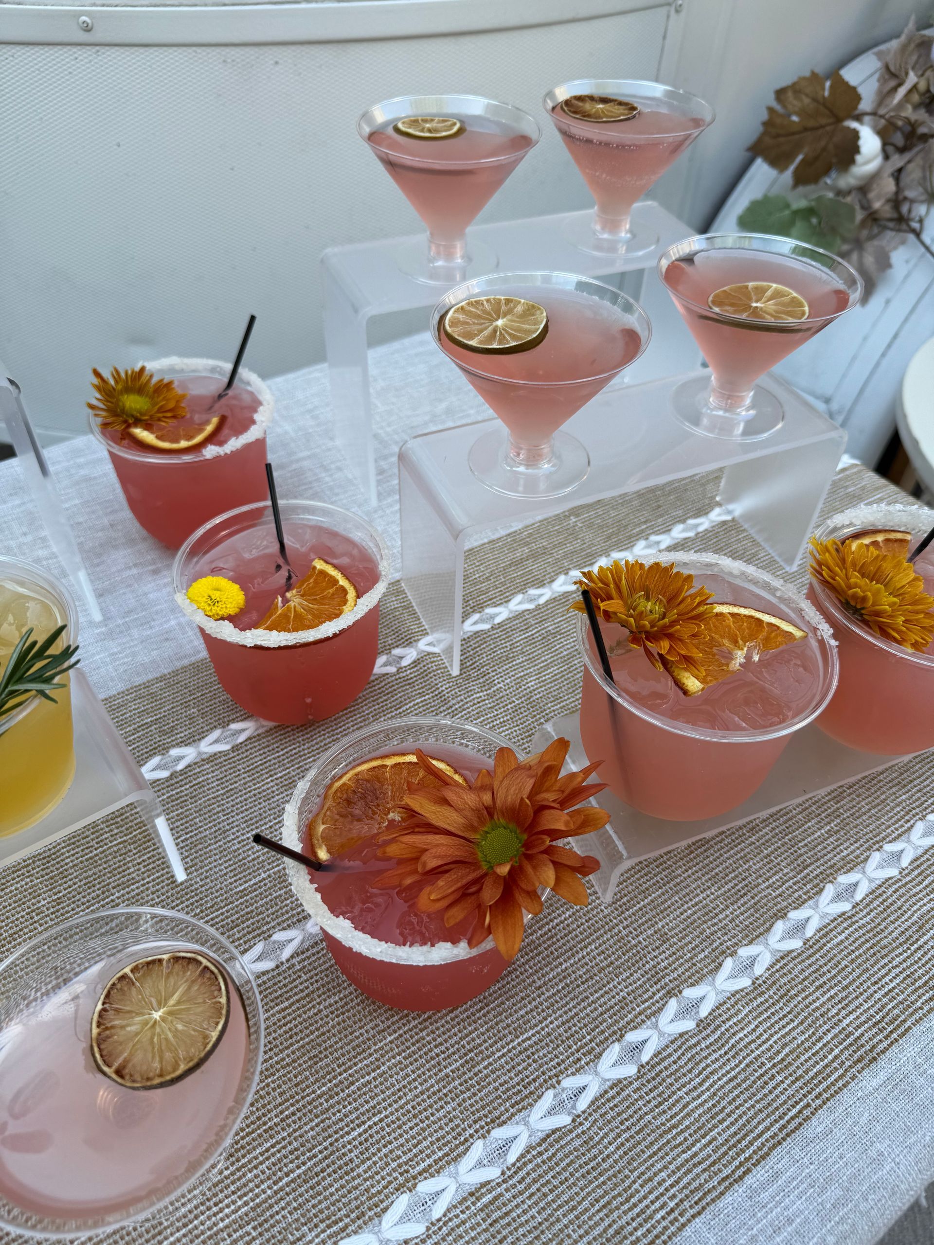 Cocktails on a table. Pink drinks with citrus and flower garnishes.