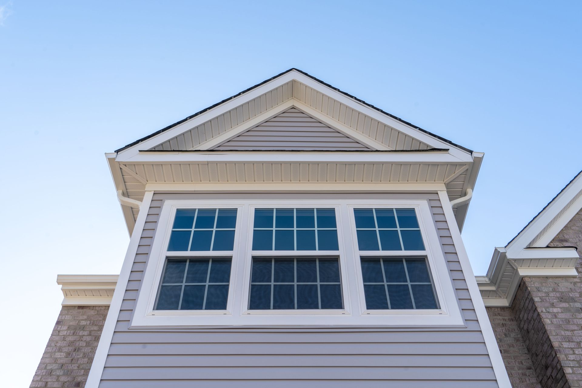White house gable with three windows against a clear blue sky