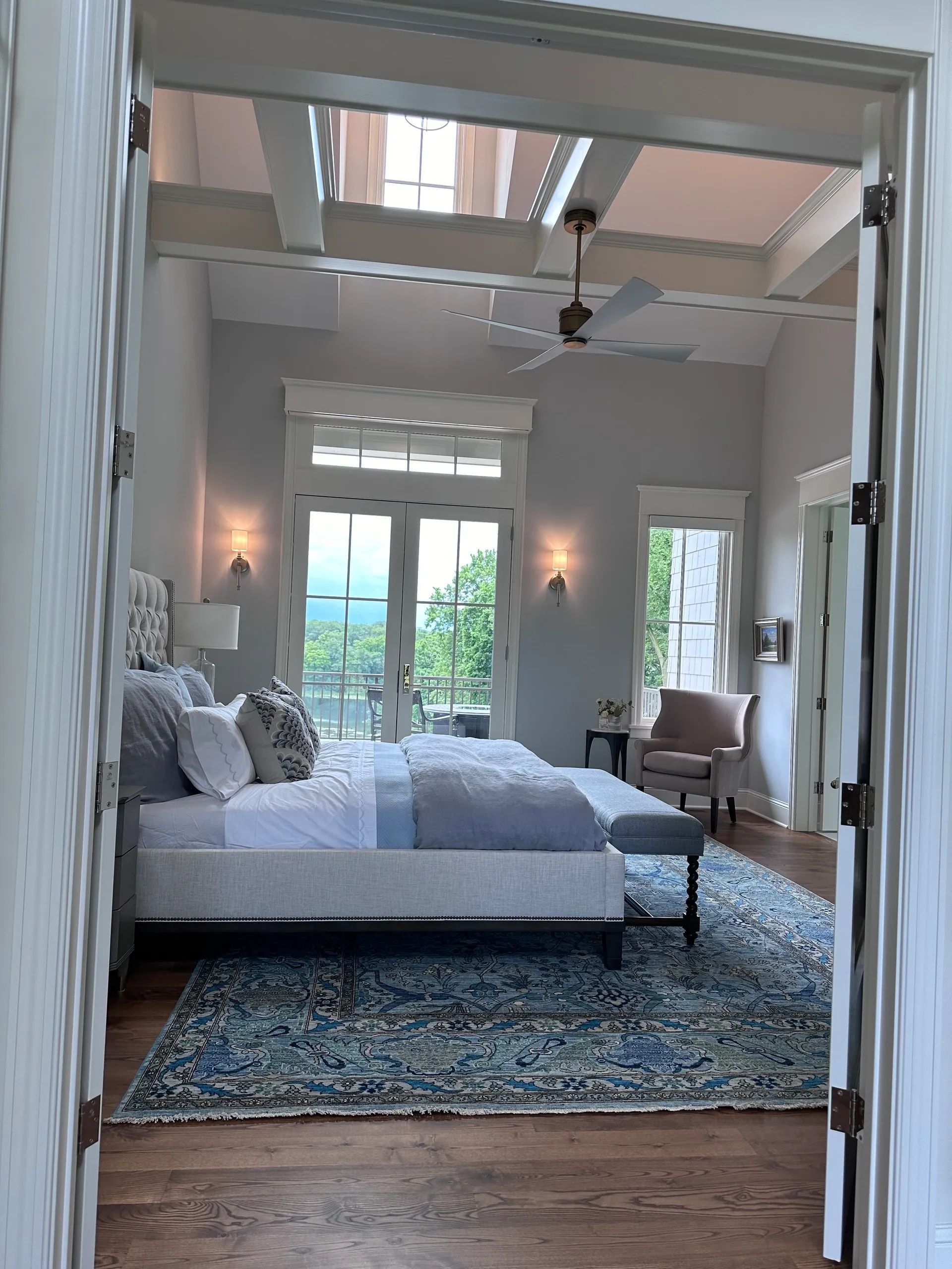Bedroom with a bed, rug, and a view of the outdoors, viewed through an open doorway.
