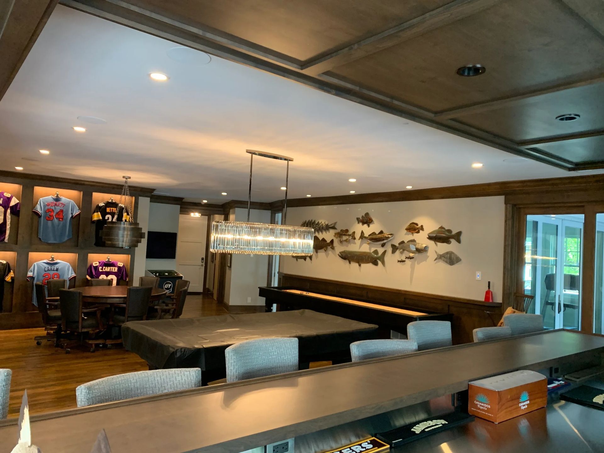 A finished basement with a pool table, bar, and sports memorabilia on display.