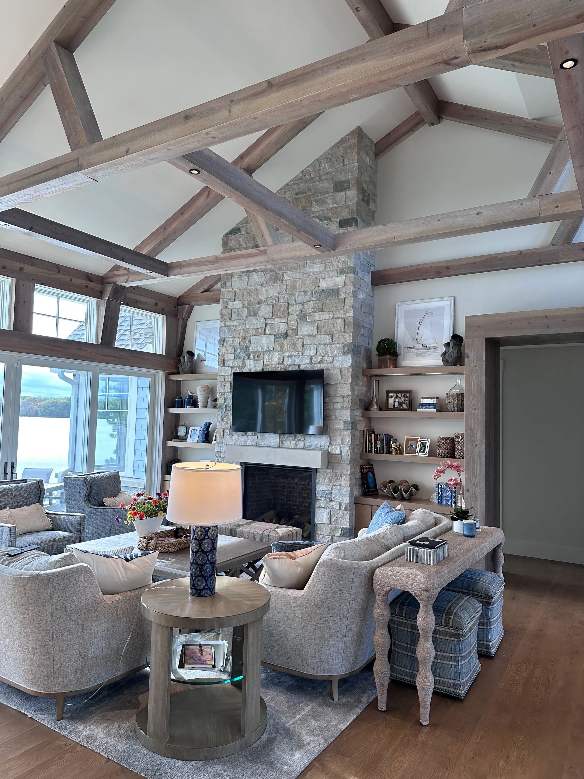 Living room with stone fireplace, vaulted ceiling, exposed beams, and comfortable seating.