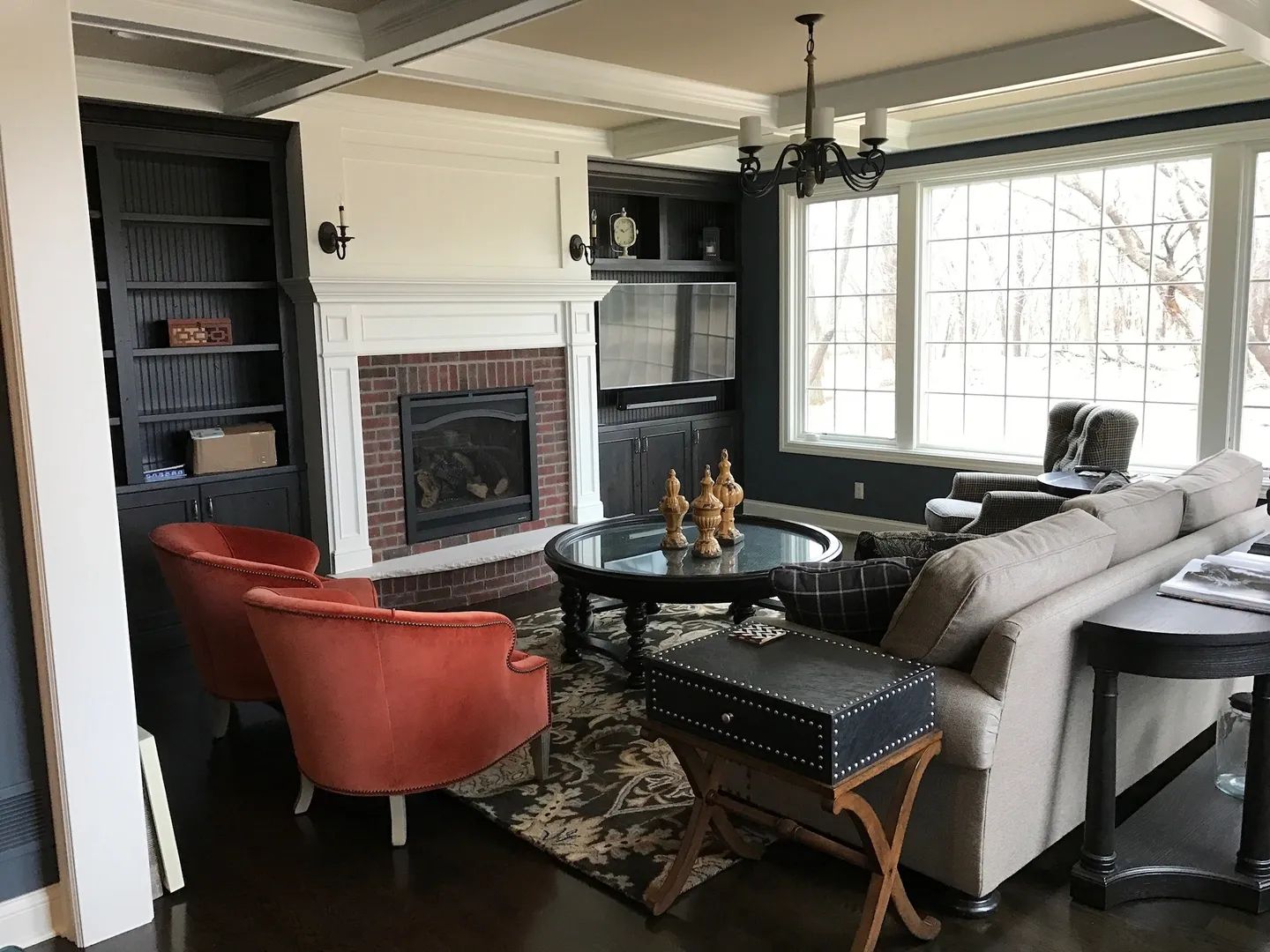 Living room with fireplace, bookshelves, orange chairs, and a sofa.