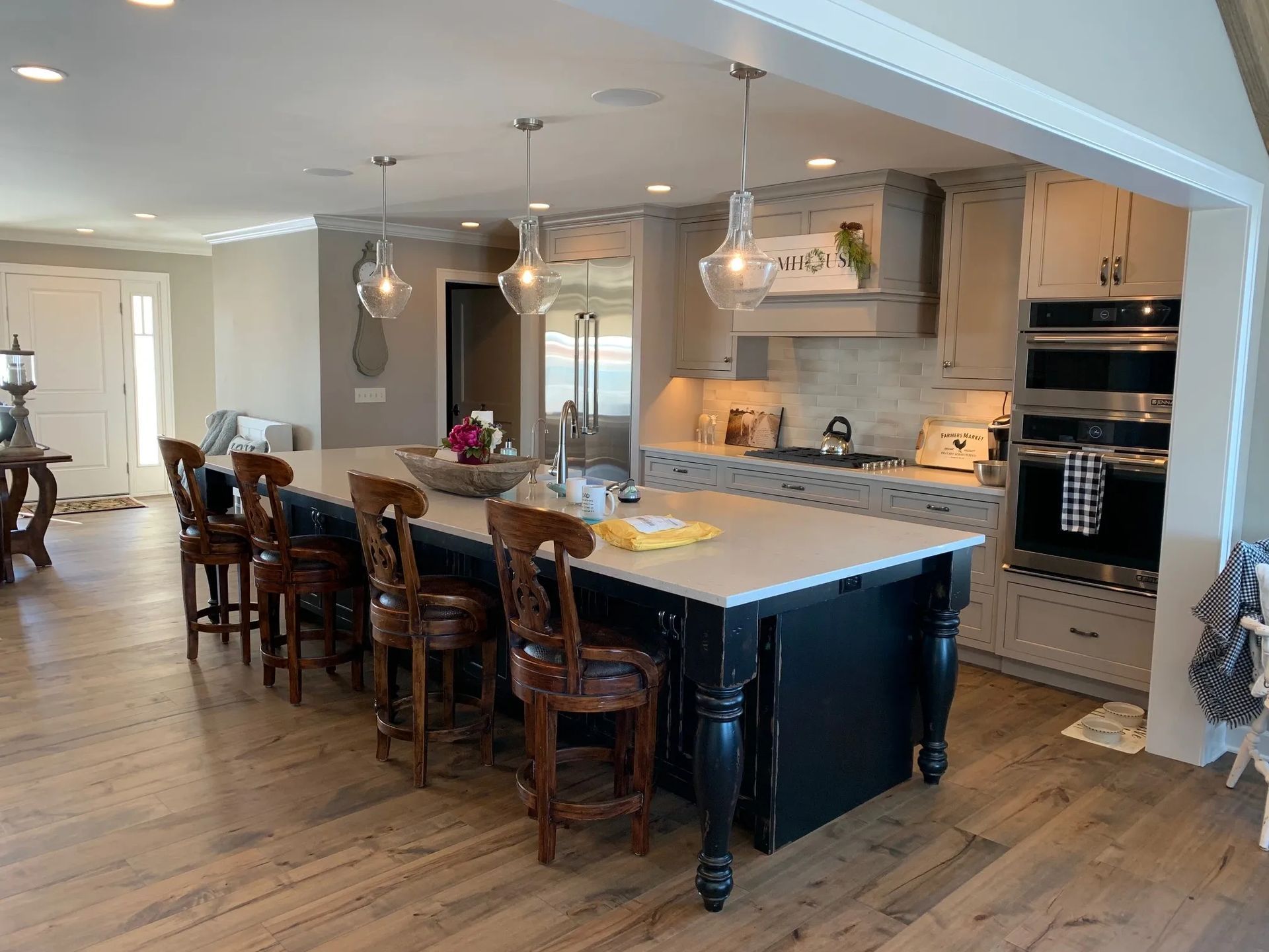Modern kitchen with a large island, light cabinets, and wood flooring.