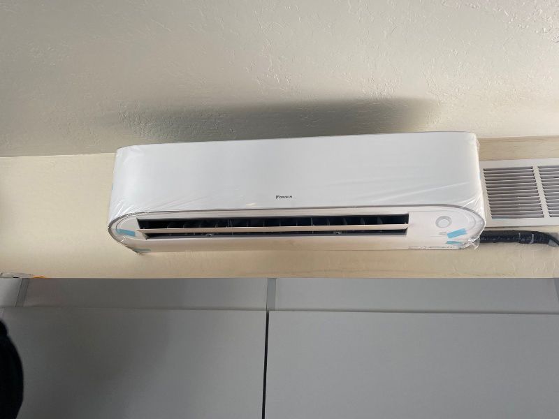 A white air conditioner is hanging from the ceiling in a room.