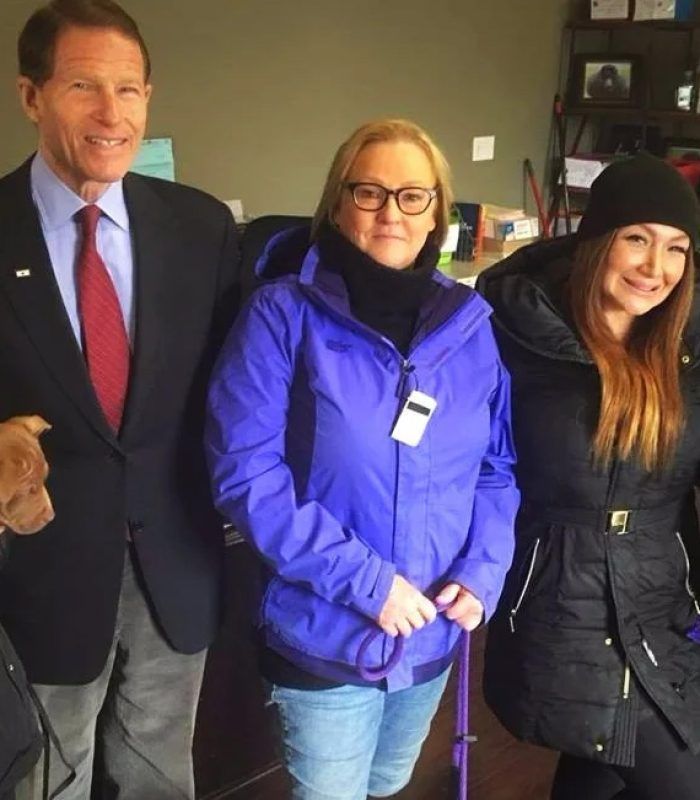 A man in a suit and tie stands next to two women