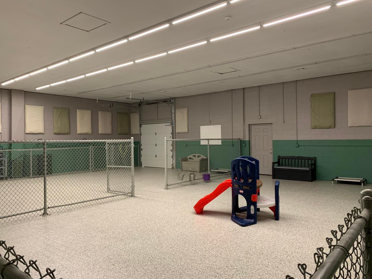 A large empty room with a chain link fence and a playground.