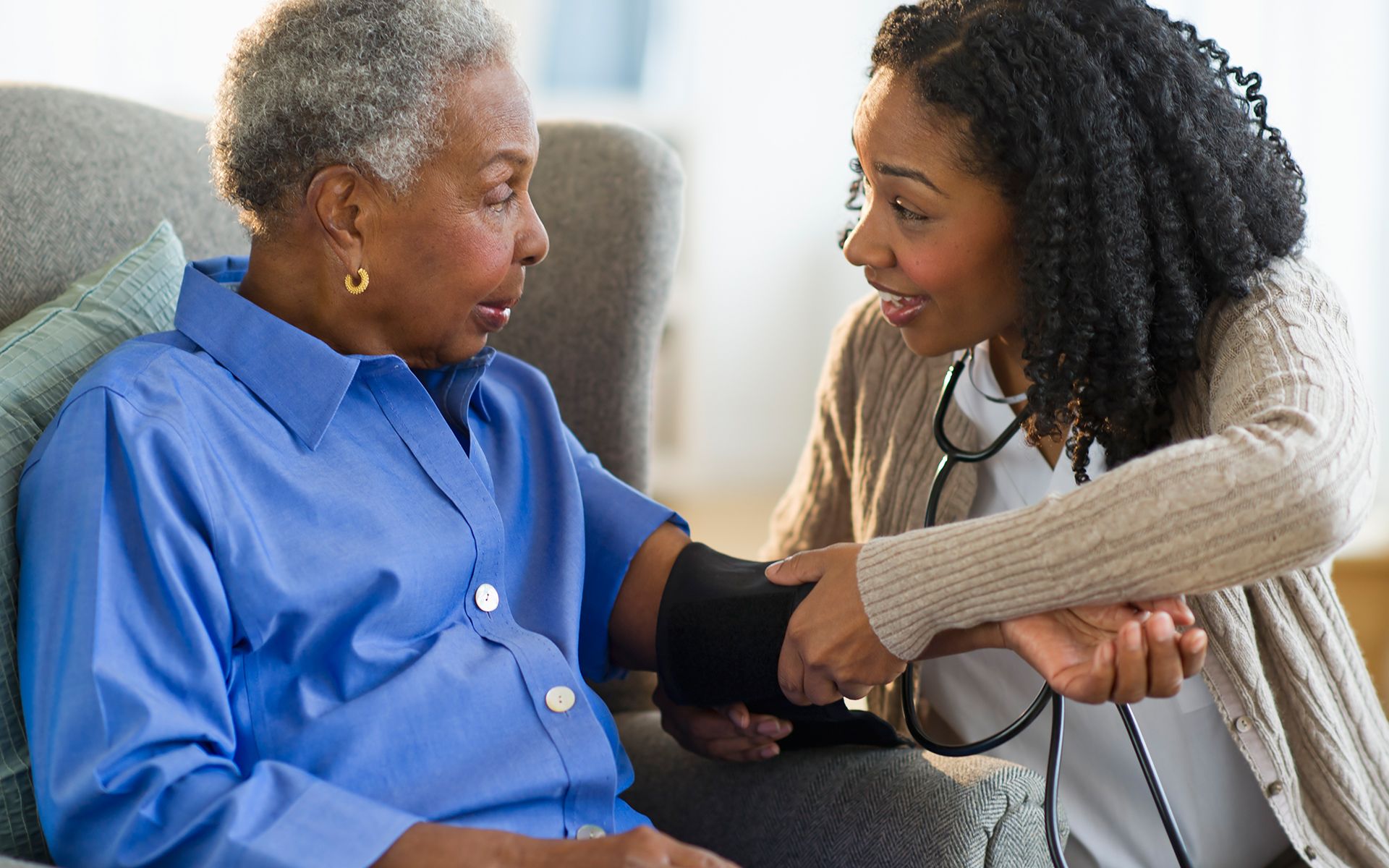 a caregiver is checking the blood pressure of an elderly woman