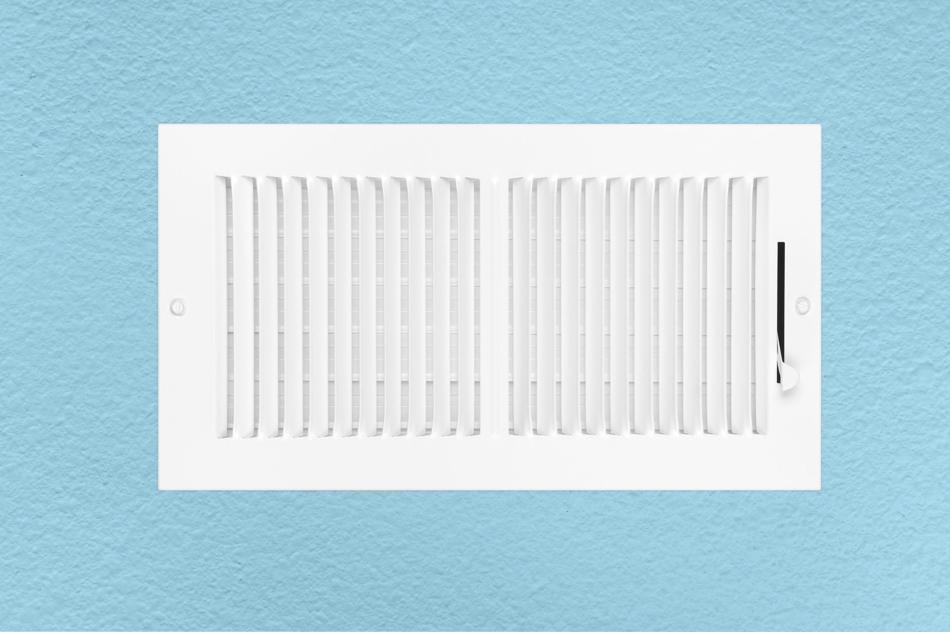 White wall vent with adjustable slats on a light blue background