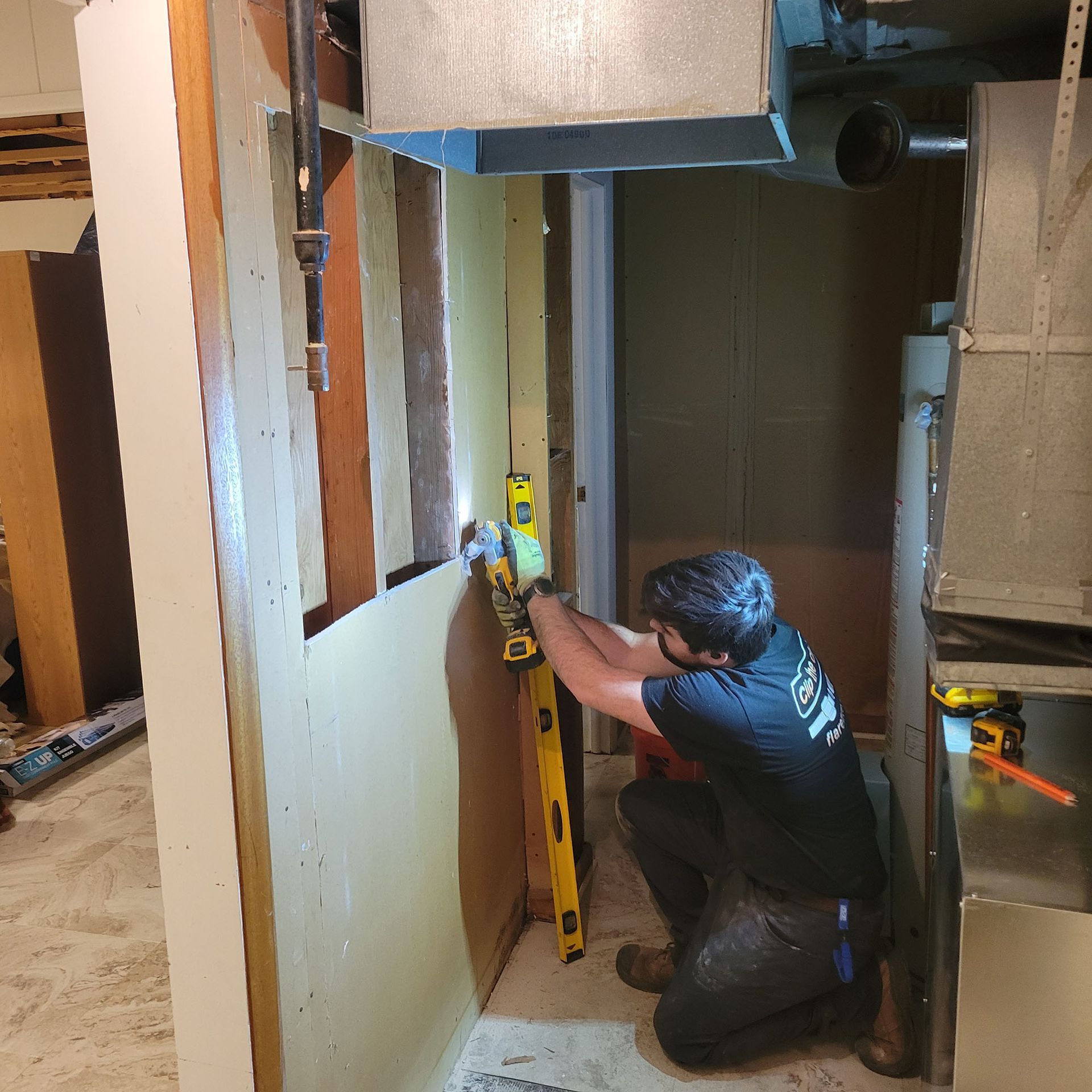 Worker using a level to align framing in a narrow indoor construction area