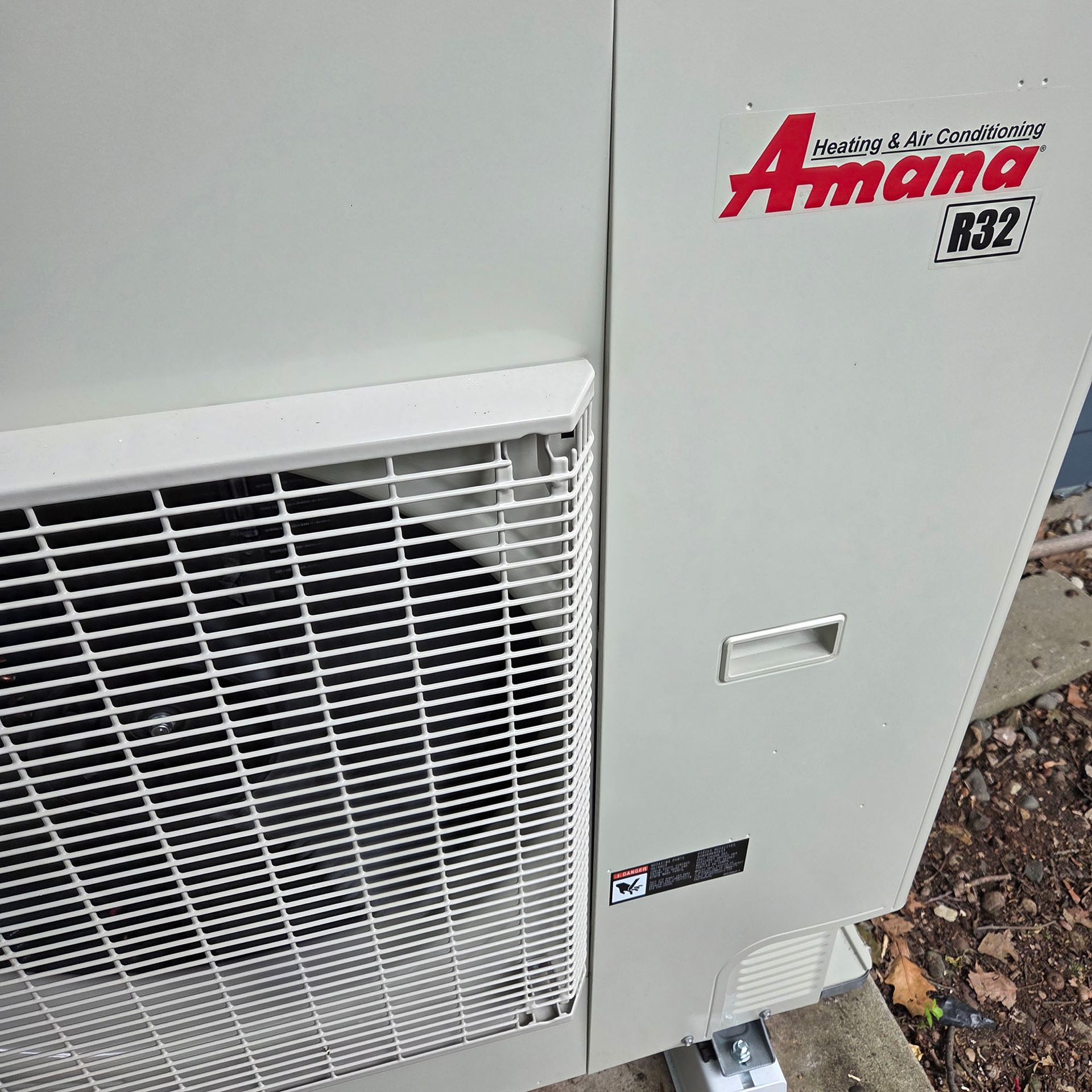 Amana outdoor air conditioner unit with white grille and gray panel