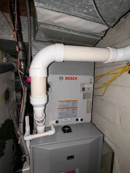 Bosch HVAC unit with white PVC vent piping in a basement utility area