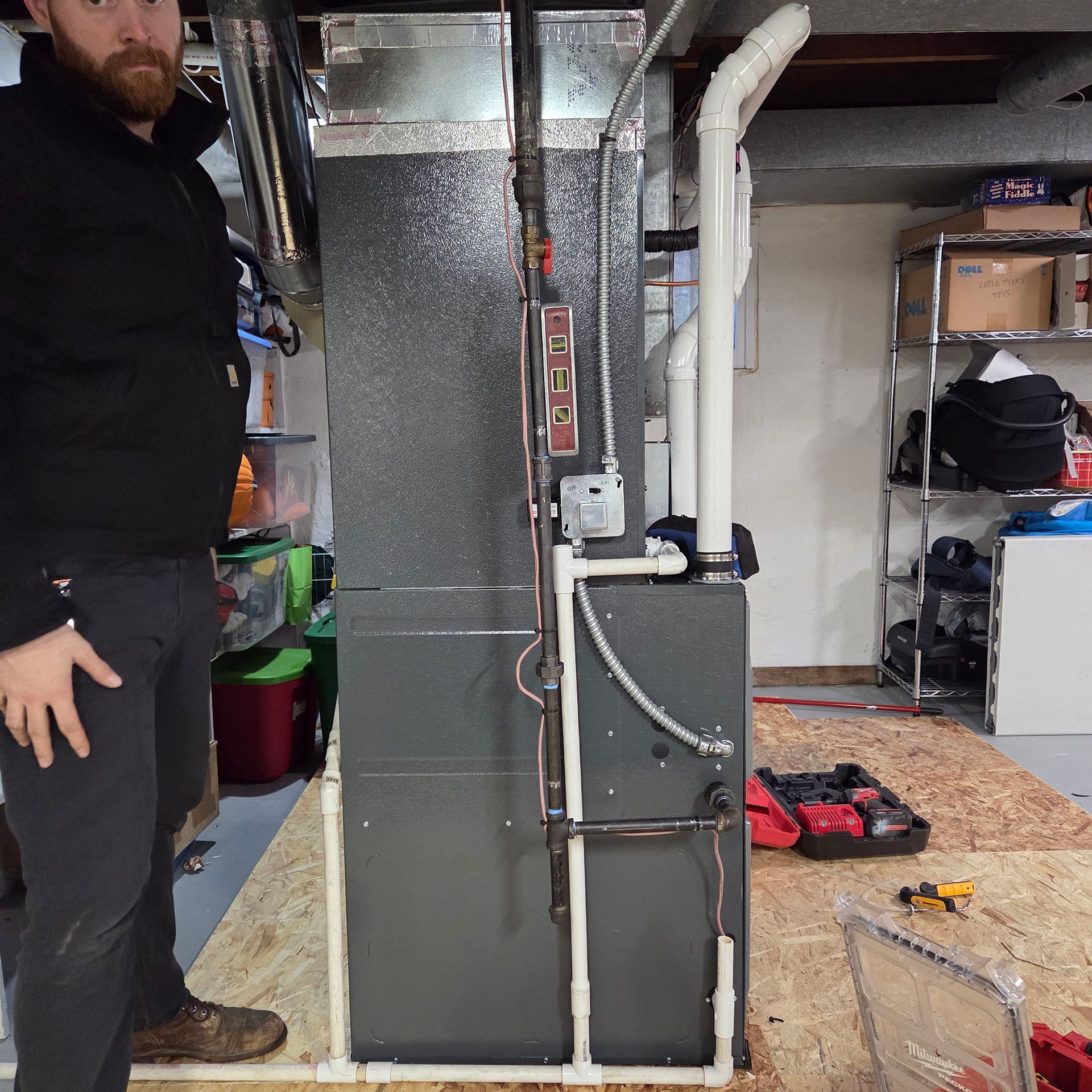 Basement HVAC furnace and ductwork beside a person standing in a utility room