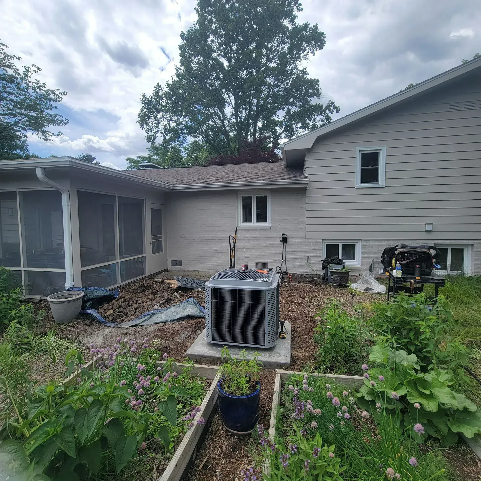 Backyard patio with screened porch, raised garden beds, and a house with siding and windows
